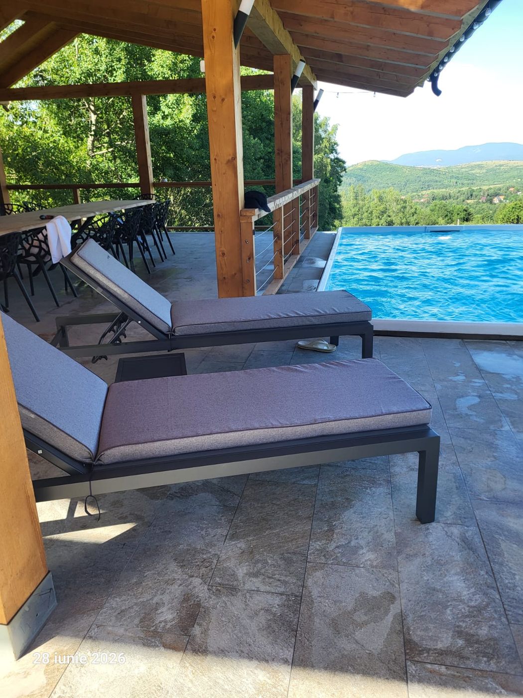 Șezlonguri pe terasa de lângă piscina încălzită, cu vedere spre munți